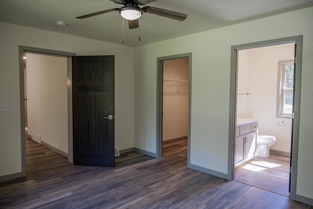 unfurnished bedroom with ceiling fan, connected bathroom, dark hardwood / wood-style flooring, a walk in closet, and a closet