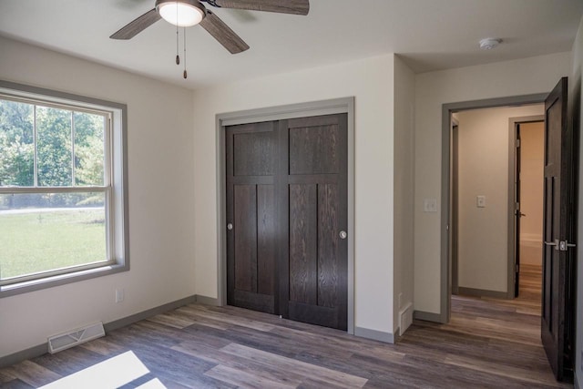 unfurnished bedroom with dark wood-type flooring, ceiling fan, and a closet