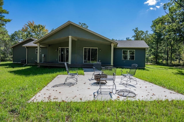 rear view of property with a fire pit, a yard, and a patio area