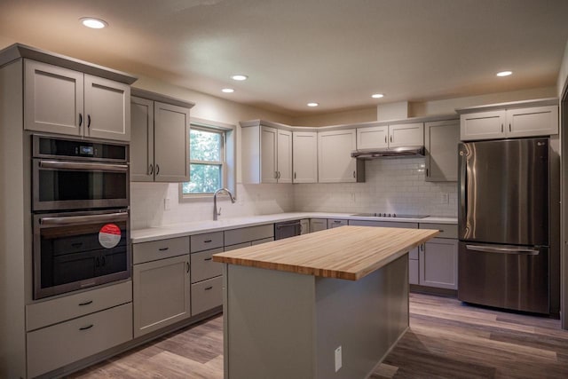 kitchen with butcher block counters, gray cabinetry, stainless steel appliances, and a kitchen island