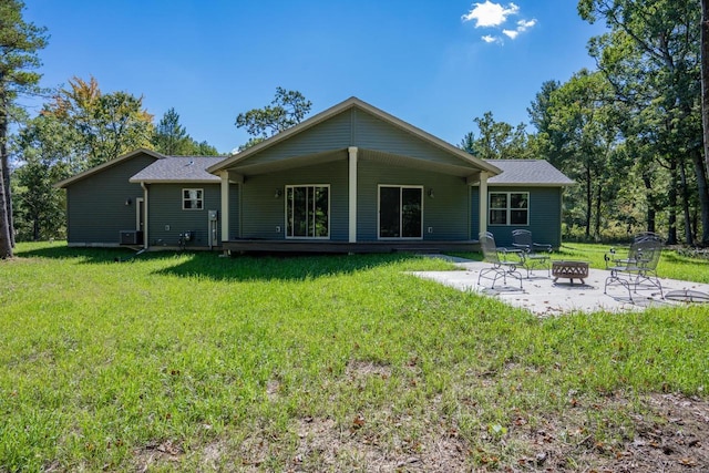 rear view of property featuring an outdoor fire pit, a patio, and a lawn