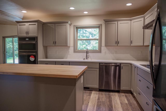 kitchen with butcher block countertops, gray cabinets, sink, and appliances with stainless steel finishes