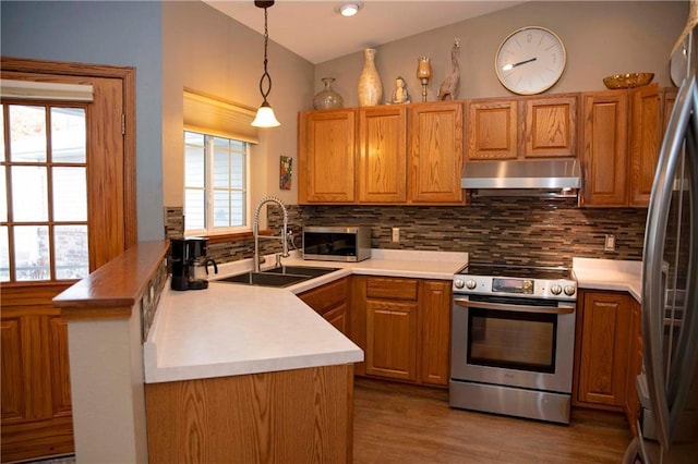 kitchen featuring sink, tasteful backsplash, kitchen peninsula, pendant lighting, and stainless steel appliances