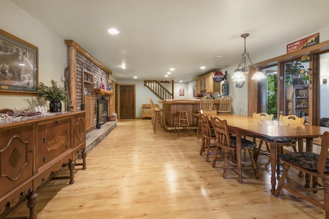 dining area with light hardwood / wood-style floors and a large fireplace