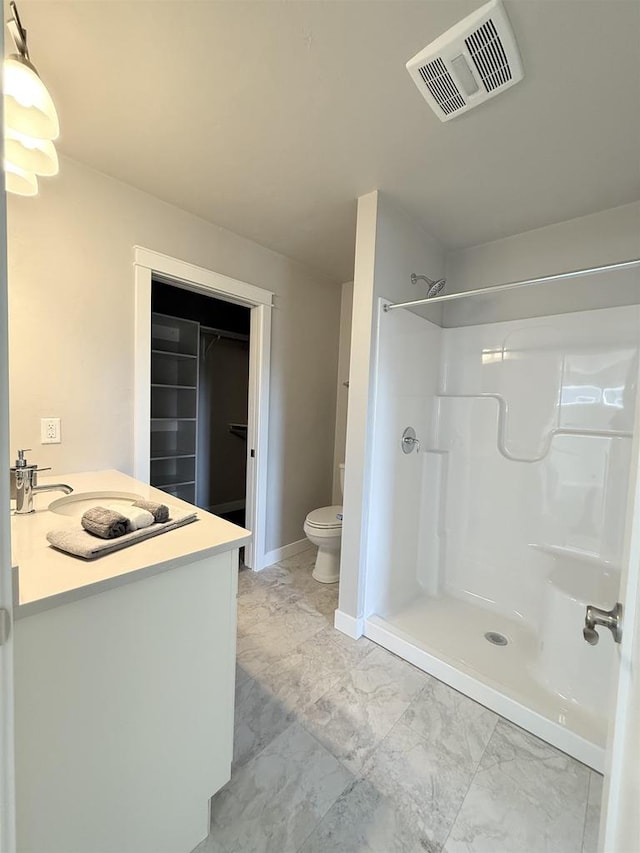 bathroom featuring vanity, a shower, and toilet