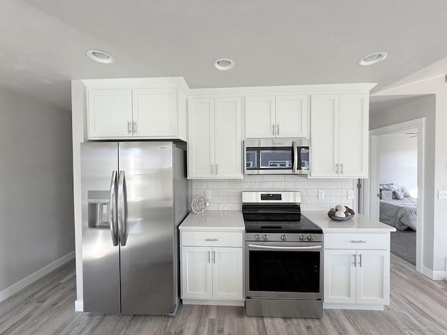 kitchen featuring backsplash, stainless steel appliances, light wood-type flooring, and white cabinets