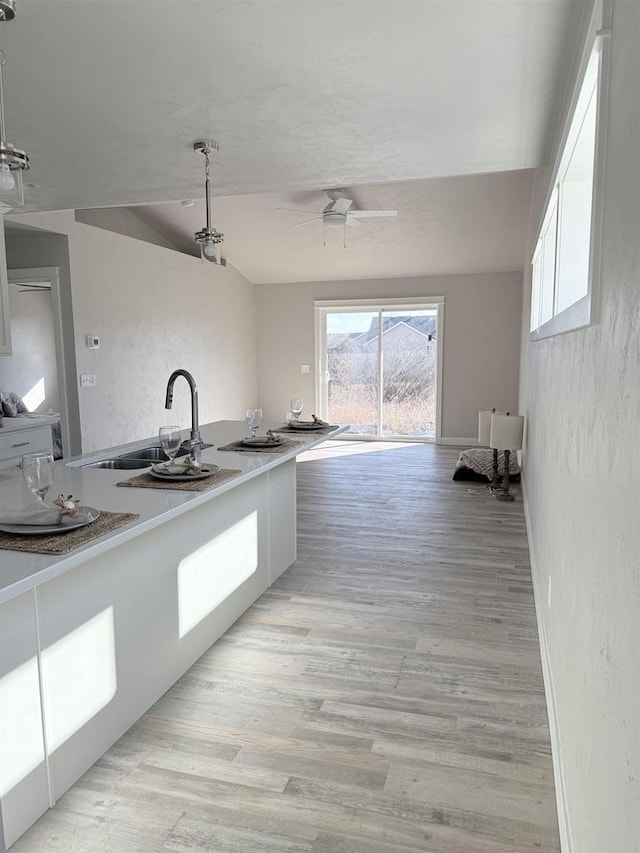 kitchen with sink, ceiling fan, white cabinets, and light wood-type flooring