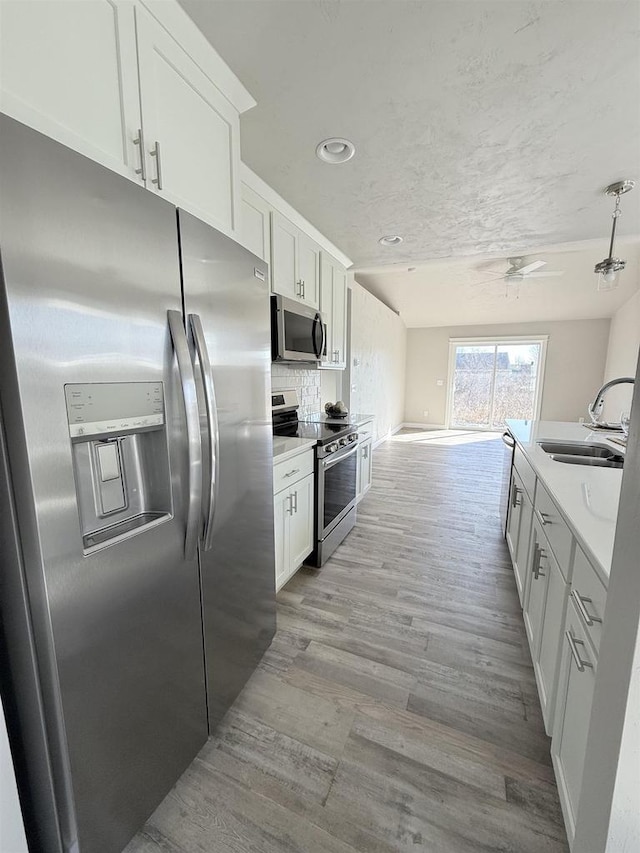 kitchen featuring white cabinetry, appliances with stainless steel finishes, sink, and light wood-type flooring