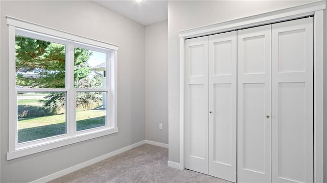 unfurnished bedroom with light colored carpet and a closet