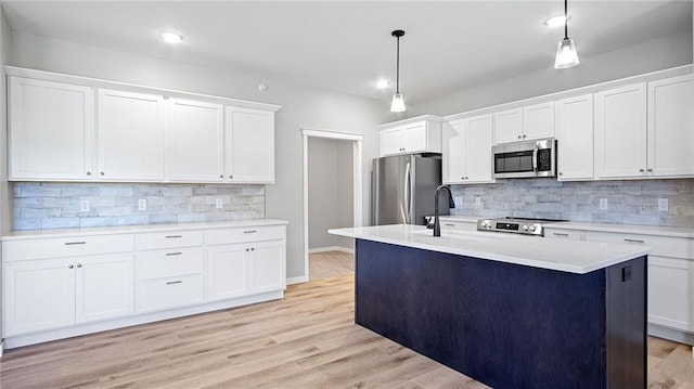 kitchen with pendant lighting, stainless steel appliances, sink, and white cabinets