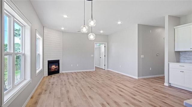 unfurnished living room with a fireplace, light hardwood / wood-style floors, and a wealth of natural light