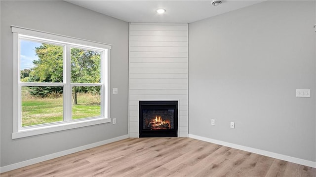 unfurnished living room featuring a large fireplace and light hardwood / wood-style floors