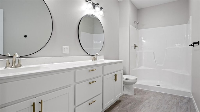 bathroom featuring vanity, hardwood / wood-style flooring, toilet, and walk in shower