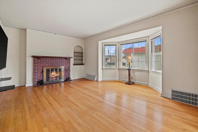 unfurnished living room featuring a brick fireplace and light hardwood / wood-style flooring