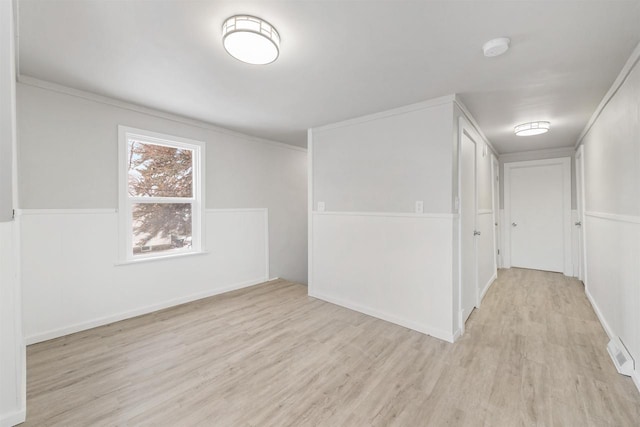 empty room with crown molding and light hardwood / wood-style flooring