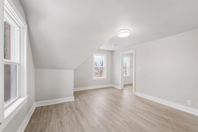 additional living space featuring lofted ceiling and light wood-type flooring