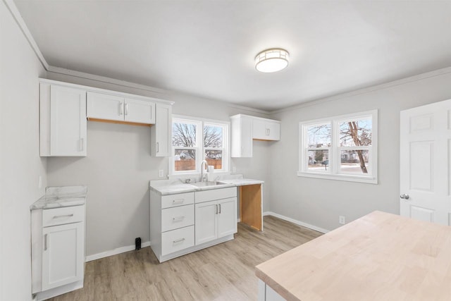 kitchen with white cabinetry, sink, light stone counters, and light hardwood / wood-style flooring