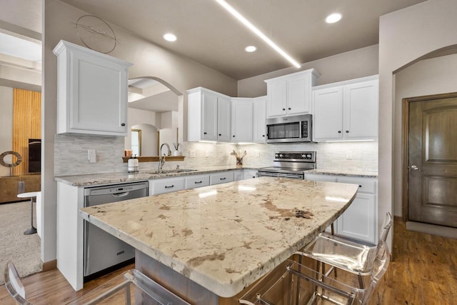 kitchen with white cabinetry, a breakfast bar area, stainless steel appliances, and a kitchen island