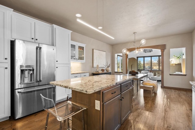 kitchen with a center island, high quality fridge, pendant lighting, and white cabinets