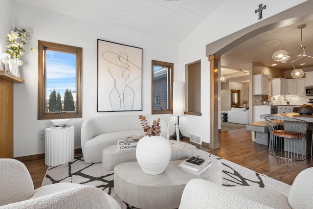 living room featuring wood-type flooring, lofted ceiling, radiator heating unit, and a chandelier