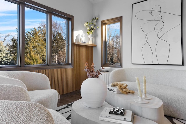 living area with radiator heating unit, a healthy amount of sunlight, and hardwood / wood-style floors