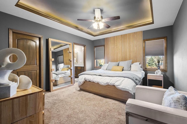 carpeted bedroom featuring ceiling fan, connected bathroom, and a raised ceiling