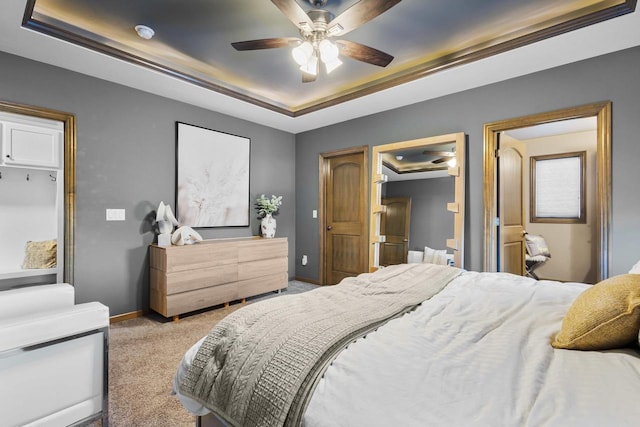 carpeted bedroom with a raised ceiling and ceiling fan