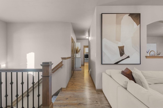 corridor with washer / dryer and light hardwood / wood-style floors