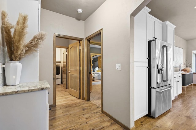 hallway with washer / dryer and light hardwood / wood-style floors