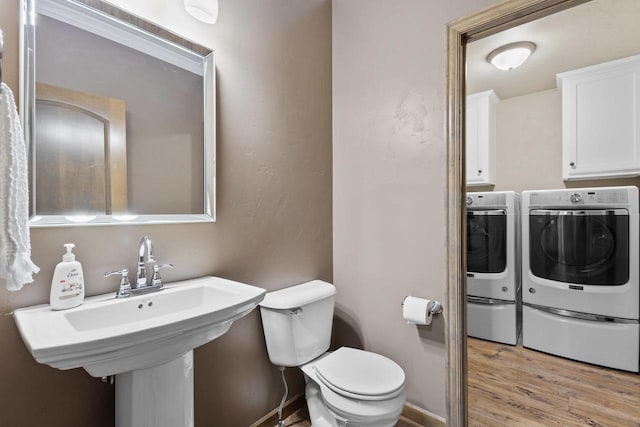 bathroom with hardwood / wood-style flooring, independent washer and dryer, toilet, and sink