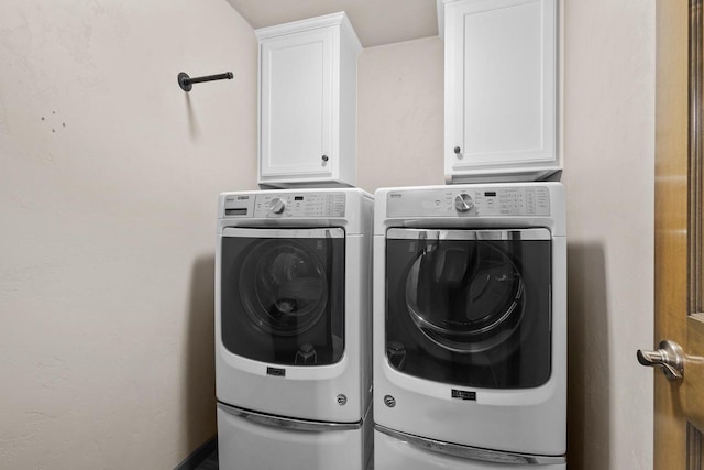 clothes washing area with cabinets and washer and dryer