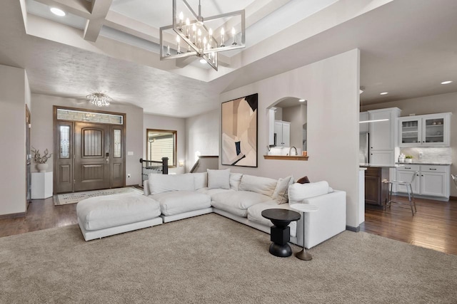 living room with coffered ceiling, dark hardwood / wood-style floors, beamed ceiling, and an inviting chandelier