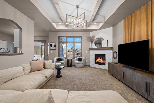 carpeted living room featuring beamed ceiling, coffered ceiling, a chandelier, and a fireplace