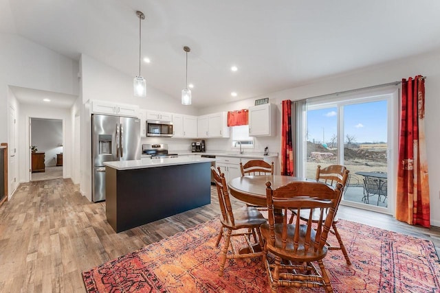 dining area with sink, high vaulted ceiling, and light wood-type flooring