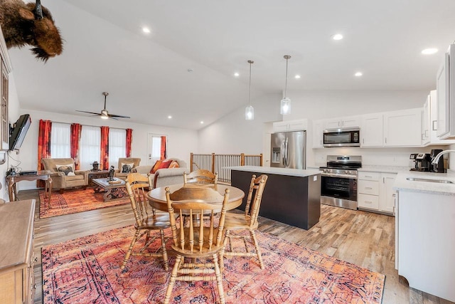 dining room featuring sink, light hardwood / wood-style flooring, high vaulted ceiling, and ceiling fan