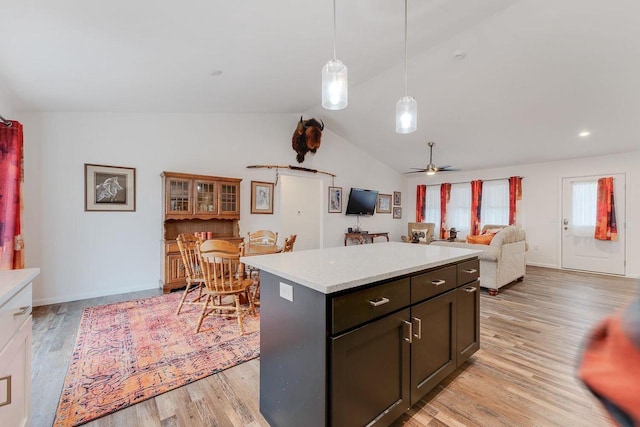 kitchen featuring dark brown cabinetry, lofted ceiling, hanging light fixtures, light wood-type flooring, and a kitchen island