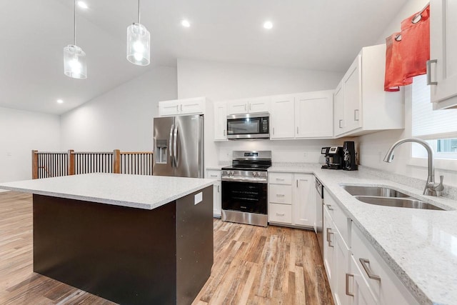 kitchen with appliances with stainless steel finishes, white cabinetry, sink, hanging light fixtures, and light hardwood / wood-style flooring