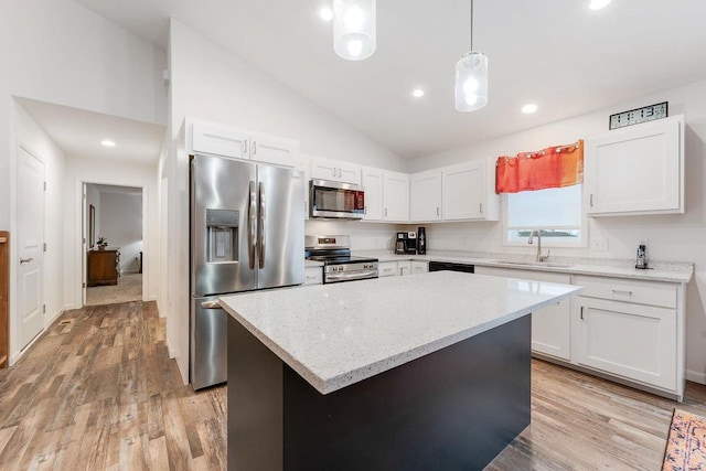 kitchen featuring white cabinetry, decorative light fixtures, stainless steel appliances, and a kitchen island