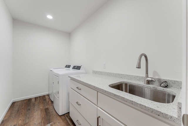 clothes washing area with cabinets, dark hardwood / wood-style floors, sink, and washing machine and dryer