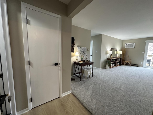 hallway featuring a baseboard heating unit, an AC wall unit, and carpet