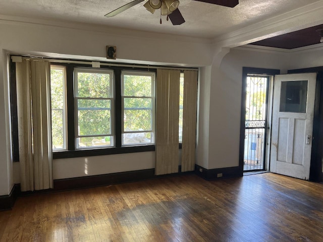 spare room with dark hardwood / wood-style flooring, a healthy amount of sunlight, crown molding, and a textured ceiling