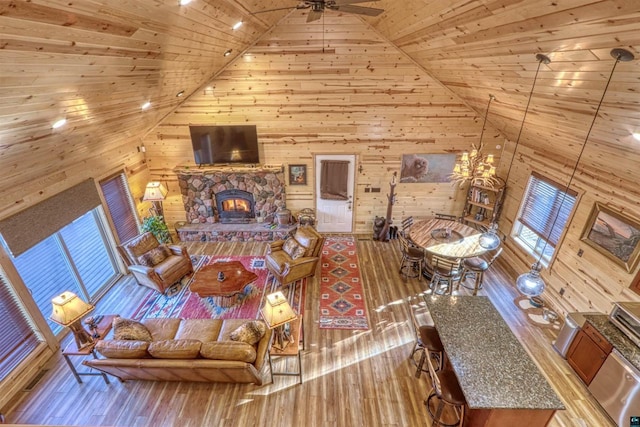 living room featuring high vaulted ceiling, wooden ceiling, wooden walls, a fireplace, and light hardwood / wood-style floors