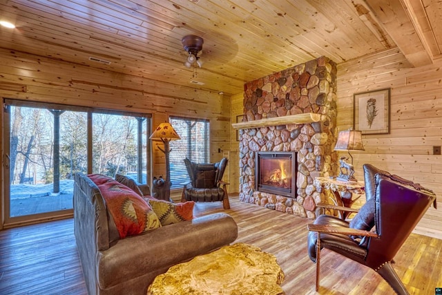 living room featuring a fireplace, light hardwood / wood-style flooring, wooden ceiling, and wood walls