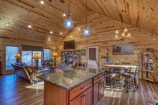 kitchen with pendant lighting, dark stone countertops, a center island, wood-type flooring, and wooden ceiling