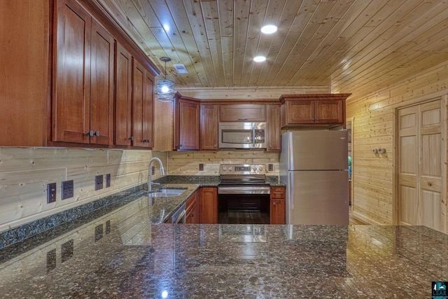 kitchen with sink, appliances with stainless steel finishes, pendant lighting, dark stone counters, and decorative backsplash