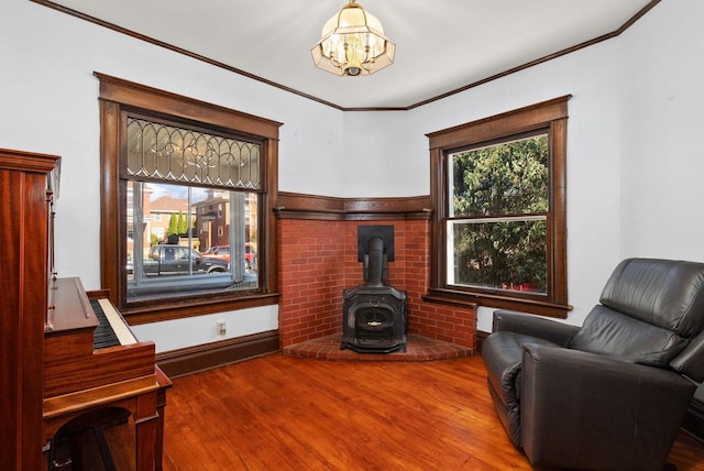 sitting room with crown molding, wood-type flooring, and a wood stove