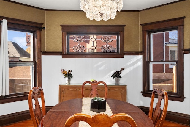 dining area featuring hardwood / wood-style flooring, ornamental molding, and a notable chandelier