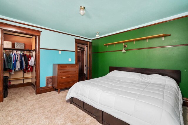 bedroom featuring a walk in closet, light colored carpet, and a closet