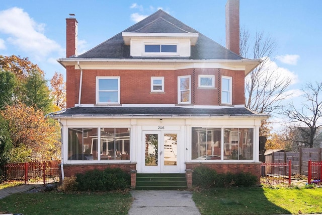 view of front of house featuring a sunroom and a front yard