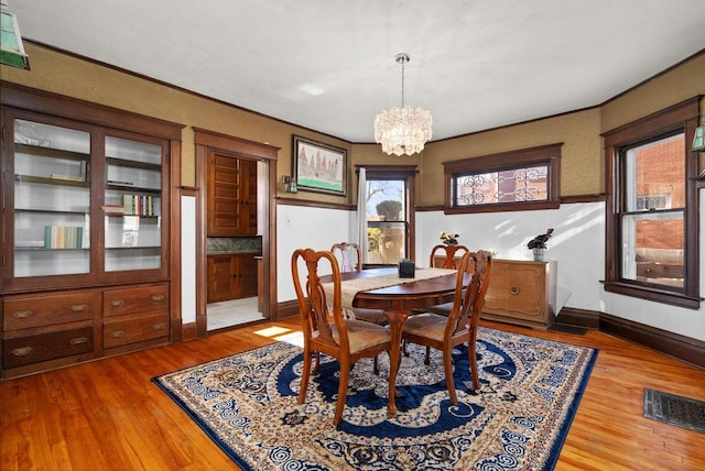 dining area featuring crown molding, hardwood / wood-style floors, and a notable chandelier